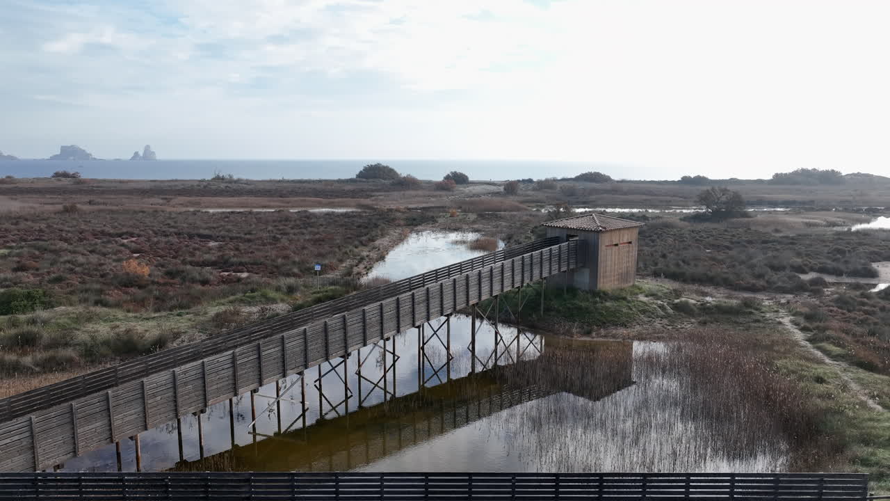 vista aérea a través de la pasarela de madera a la cabaña de observación de observación de aves en la reserva natural de la costa de la costa brava