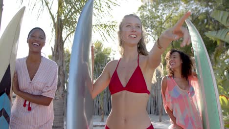 retrato de un grupo feliz y diverso de amigos sosteniendo tablas de surf en una playa soleada