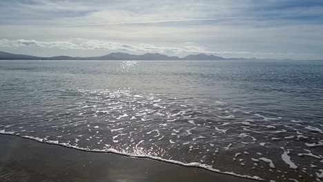 Nebulosa-Cordillera-De-Snowdonia-A-Través-Del-Idílico-Y-Brillante-Paisaje-Marino-Irlandés-En-Cámara-Lenta-Desde-La-Costa-De-La-Playa-De-Newborough