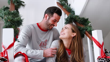 Porträt-Eines-Aufgeregten-Paares-Im-Schlafanzug,-Das-Am-Weihnachtsmorgen-Auf-Der-Treppe-Sitzt