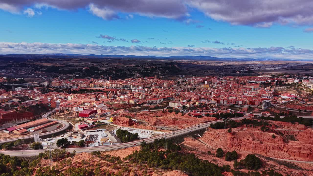 Udsigt over en by i Spanien omgivet af røde bakker og blå himmel