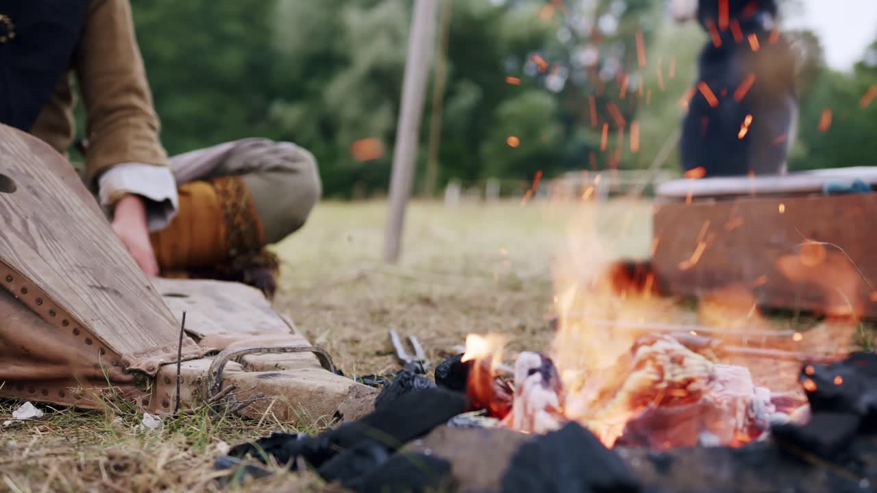 중세 캠프에서 모닥불을 피우기 위해 느린 동작으로 두 개의 나무 풀무를 흔드는 사람