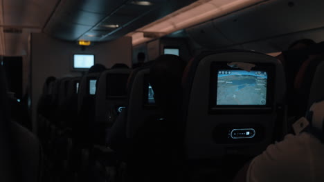 People-traveling-by-blane-at-night-Dark-cabin-with-working-seat-monitors