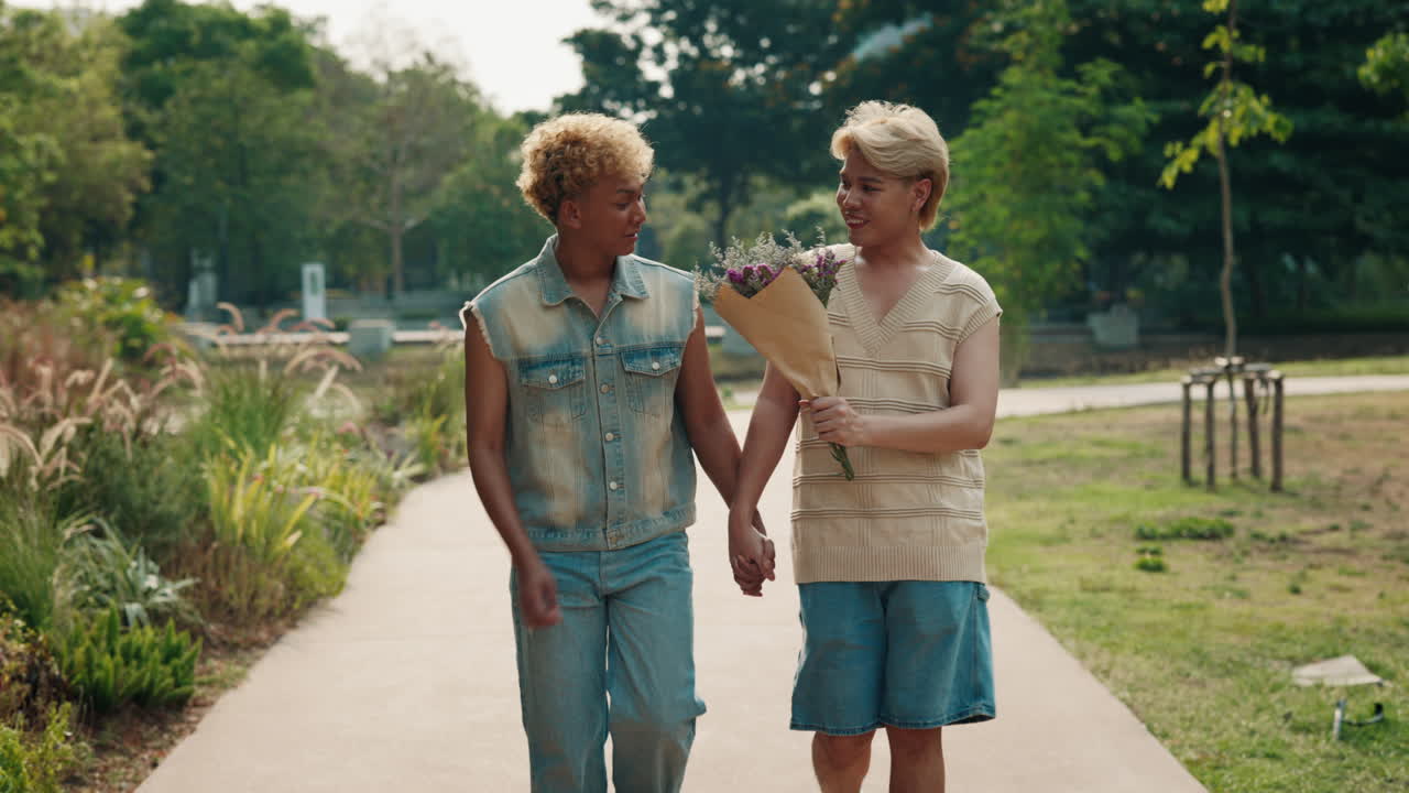 A loving LGBTQ couple walking hand in hand in a park