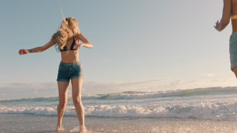 Dos-Mujeres-En-La-Playa-Salpicándose-Agua-De-Mar-Divirtiéndose-Adolescentes-Jugando-En-Un-Cálido-Día-De-Verano-Junto-Al-Océano-Disfrutando-De-Las-Vacaciones-De-Verano