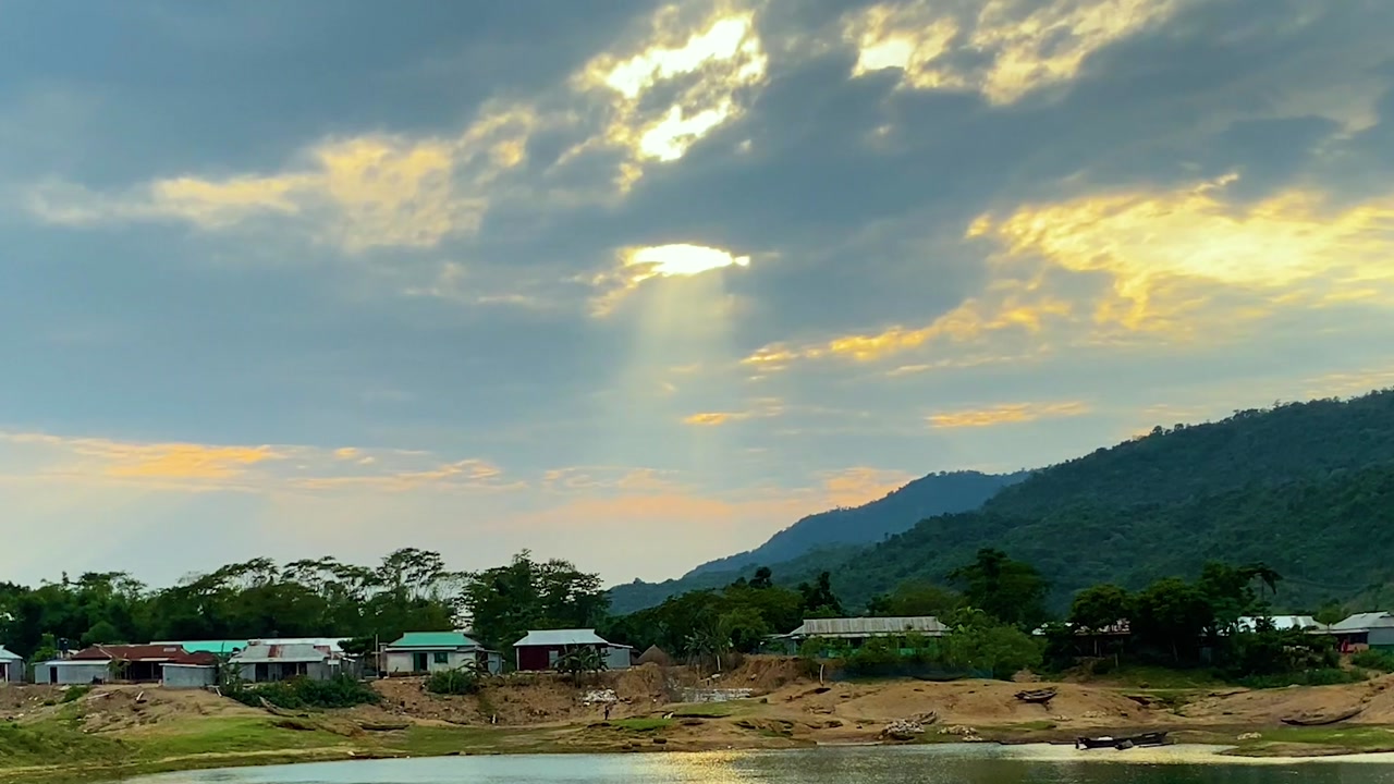 Peaceful hillside village by calm lake with mountain at sunset in sylhet, bangladesh.