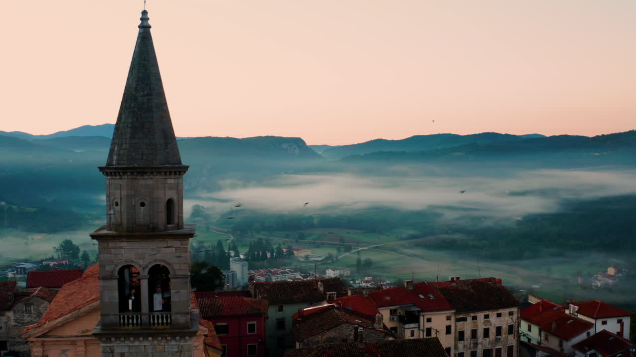 colinas nubladas con la iglesia parroquial de la santísima virgen maría en la antigua ciudad de stari grad en buzet durante la mañana nebulosa en istria, croacia