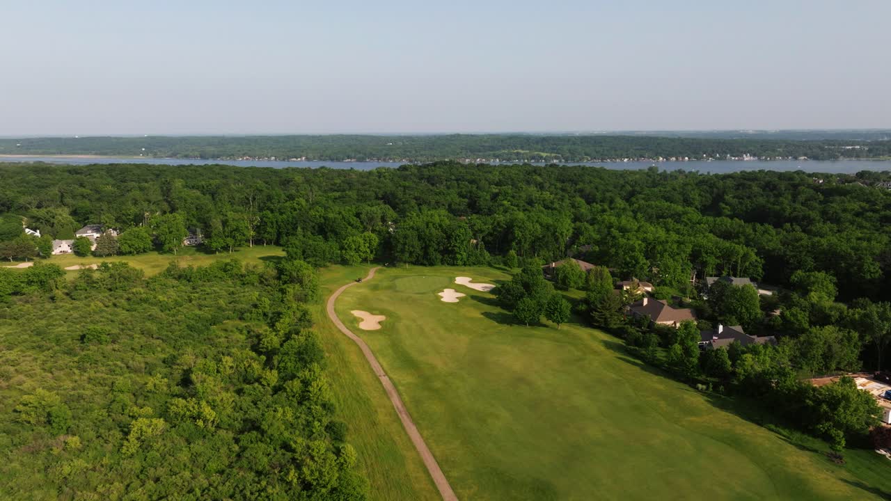 Aerial establishing pullback of golf course fairways and sand bunkers with manicured green grass