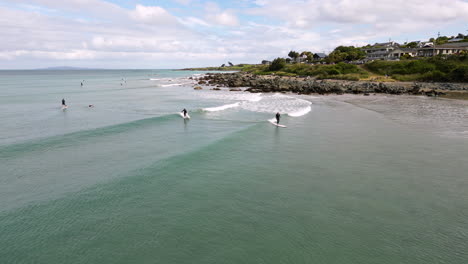 aerial view of two surfers learning how to surf on riverton new zealand beach