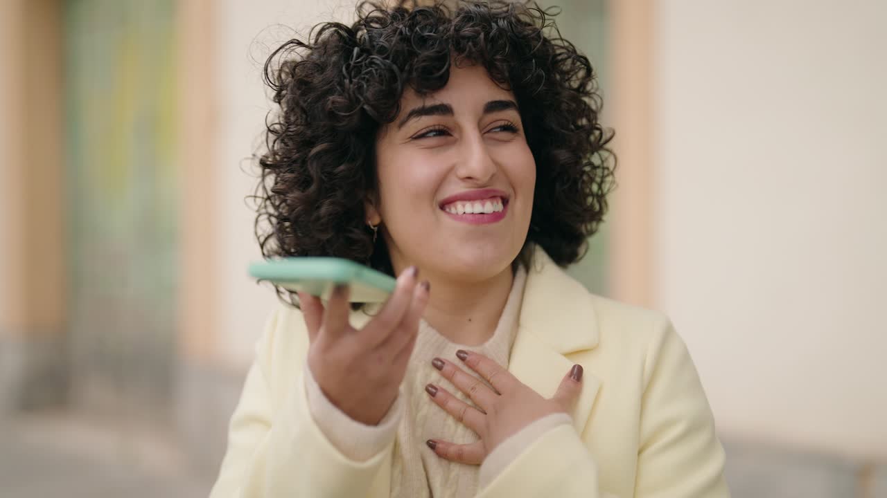Young woman smiling confident talking on the smartphone at street