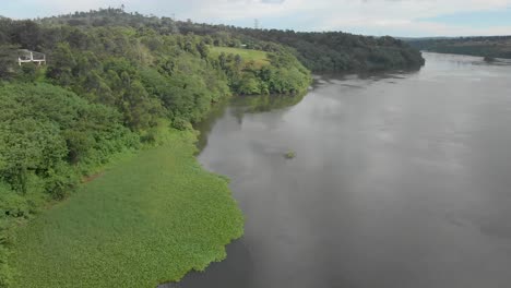 Toma-Aérea-Desde-Lo-Alto-Volando-Sobre-El-Río-Nilo-Con-La-Exuberante-Vegetación-Que-Crece-A-Lo-Largo-De-Las-Orillas