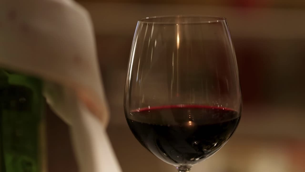 A detailed view of a wine glass filled with red wine, set against a softly blurred background.