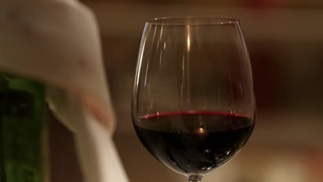 a detailed view of a wine glass filled with red wine, set against a softly blurred background.