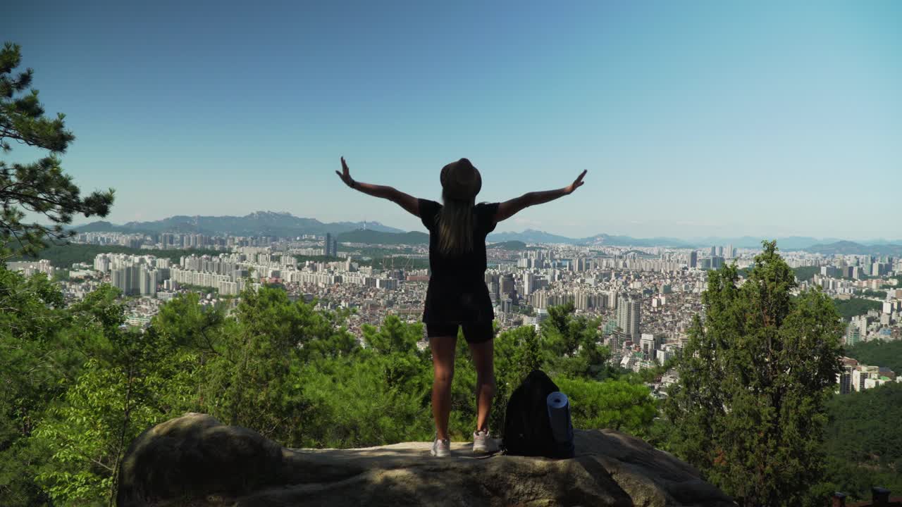 sexy lady standing on the rock raises her hands in the air at gwanaksan  mountain in seoul, south korea