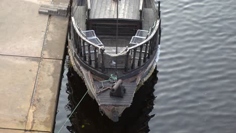 rusty cannon on medieval ship floating next to the quay, slow motion, high angle