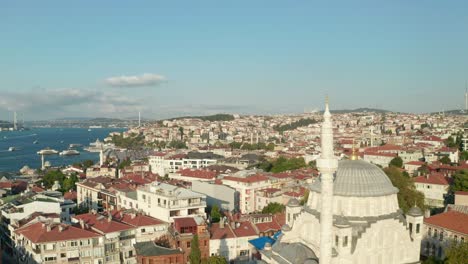 passing a mosque in istanbul neighbourhood with bosphorus and bridges in background, aerial establishing shot