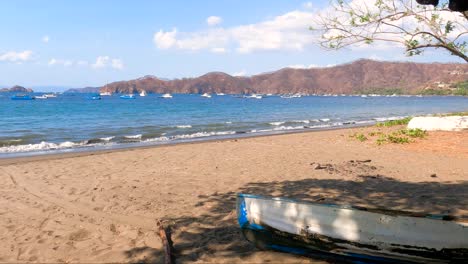 bote de madera en una playa tropical con árboles de hojas verdes en un día soleado, playa coco en guanacaste, costa rica