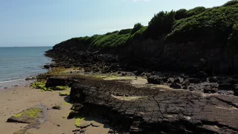 Aerial-view-Traeth-Lligwy-Jurassic-rocky-weathered-rugged-Anglesey-coastal-formation,-low-forward-push-in