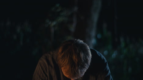 man participating in a mystical night ritual with a branch crown