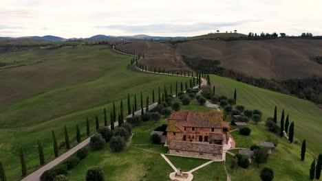tuscany countryside aerial shot with drone at sunset time - farmhouse, hills fields, vineyards, cypress trees along white road