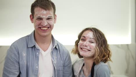 Portrait-of-cute-positive-couple-with-smudged-with-flour-face-standing-in-the-kitchen.-Happy-young-couple-fooling-around-while-cooking-food.-Close-up