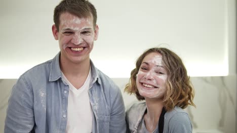 portrait of cute positive couple with smudged with flour face standing in the kitchen. happy young couple fooling around while cooking food. close up