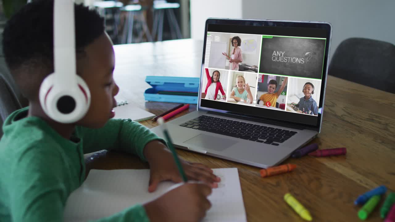 Schoolboy using laptop for online lesson at home, with diverse teacher and class on screen