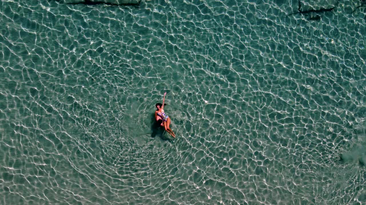 Aerial Top View over Romantic Couple Spinning Freely in Crystal Clear Waters, Paros