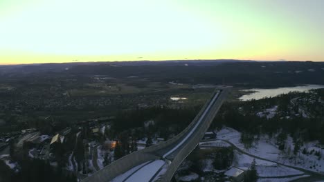 Holmenkollen-Schanze-Drohne-Zurückziehen,-Oslo-City-Mit-Norwegischem-Meer-Im-Hintergrund,-Vinterpark-Winterpark-Tryvann-Mit-Nordischem-Langlauf-Bei-Sonnenuntergang