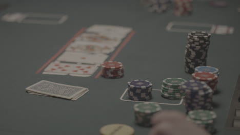 traveling shot around the cards of a poker table in slowmotion with cards and chips in the foreground log