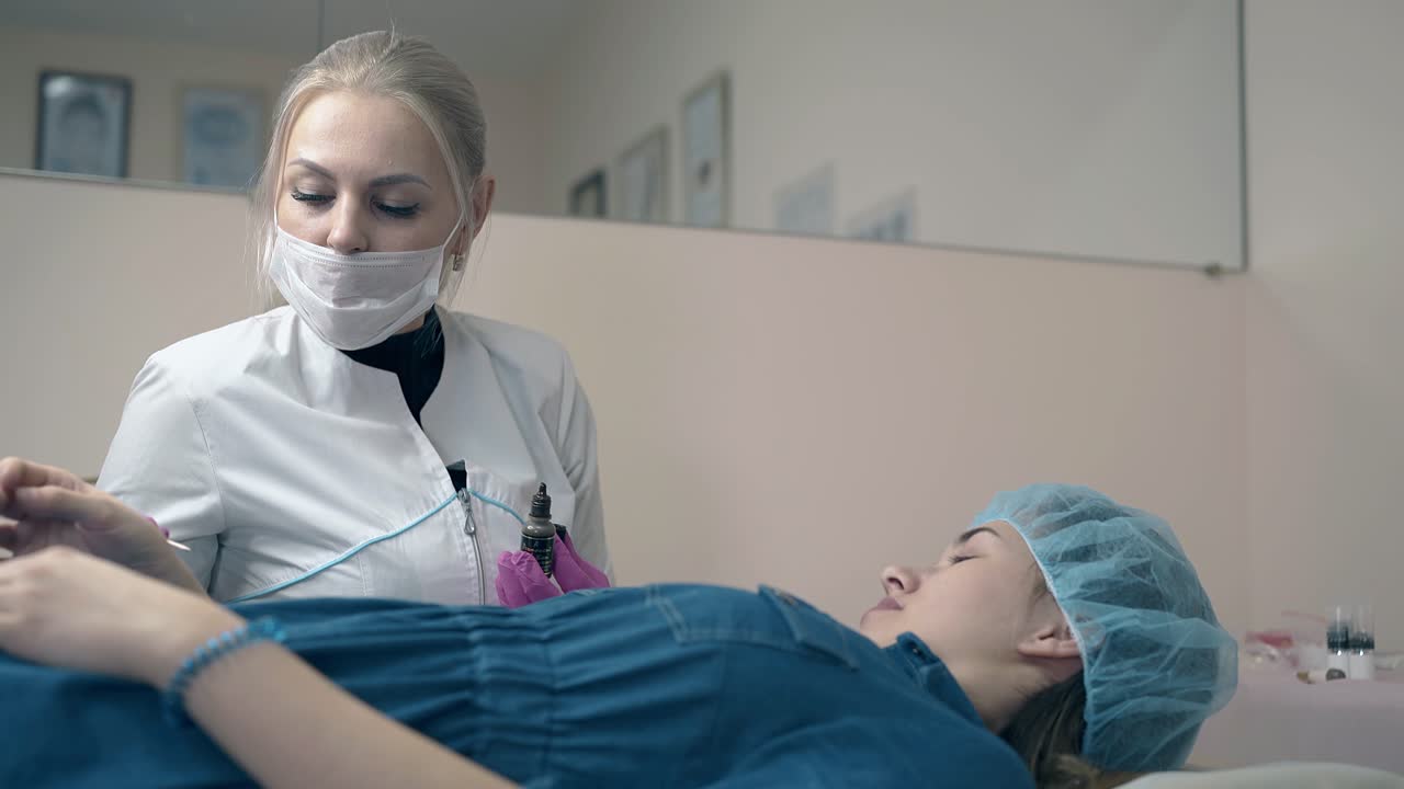 cosmetólogo con cliente elige el color para el tatuaje de la ceja