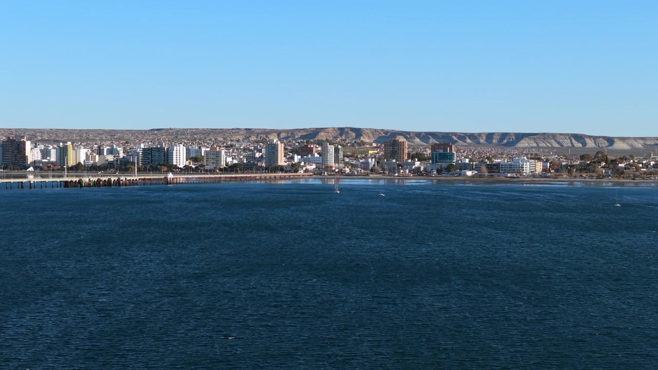 En vacker vidsträckt utsikt över havsbukten och stadsbyggnader längs kusten i Puerto Madryn.