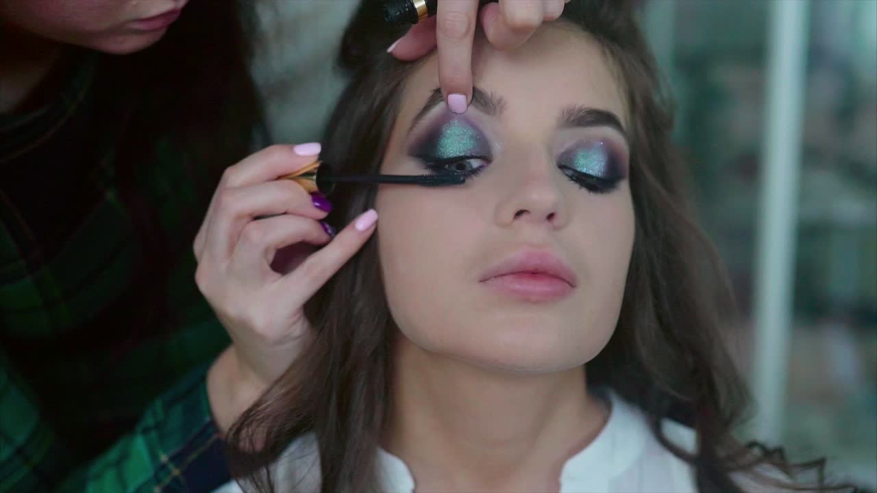 artista de maquillaje aplicando sombra de ojos brillante