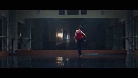 a young woman practices modern dancing and ballet in a moody room full of mirrors