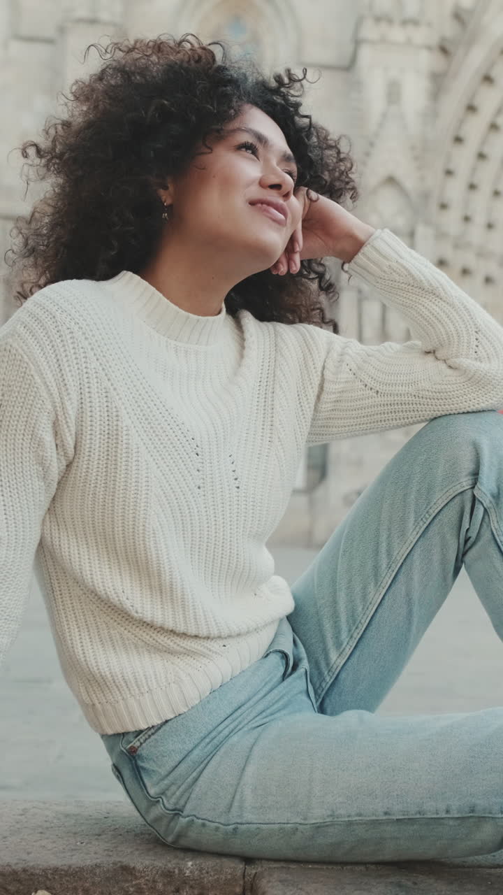 Kvinde i sweater og jeans sidder og dagdrømmer