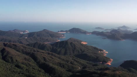 aerial view left to right of lush green vegetation over mountainous terrain in hong kong geographical park in sai kung on a beautiful sunny day