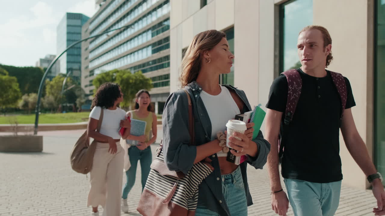 Side view of two female and male students walking around the city, going down