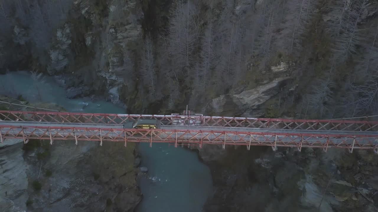 Car driving across bridge over a canyon along a four wheel drive track during sunset.