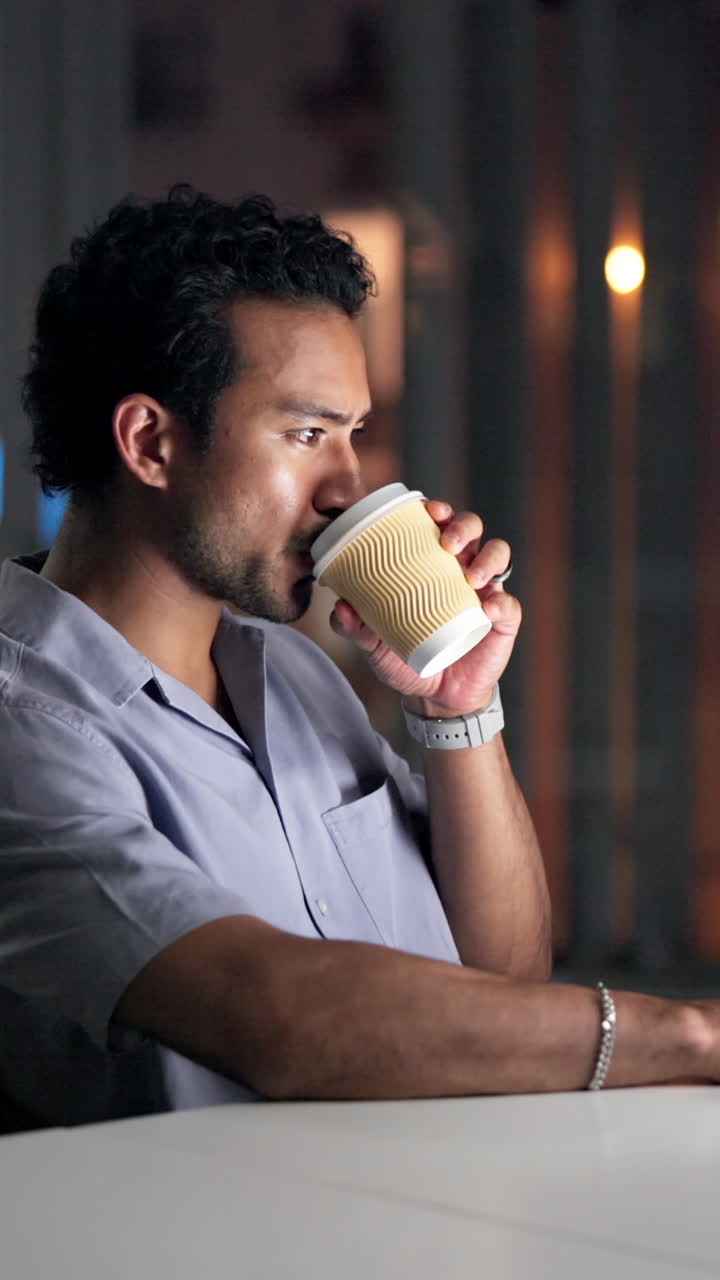 Ung mand drikker kaffe og ser fokuseret ud indendørs.