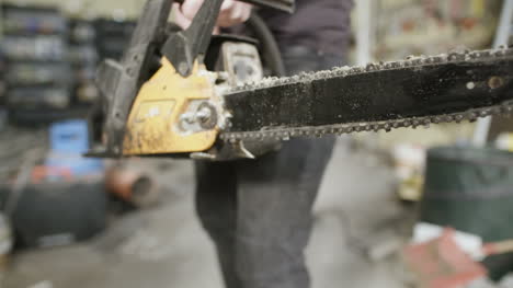 young craftsman starting powered chainsaw in workshop 1