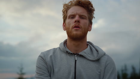 sportsman posing at camera after training. athlete standing against cloudy sky