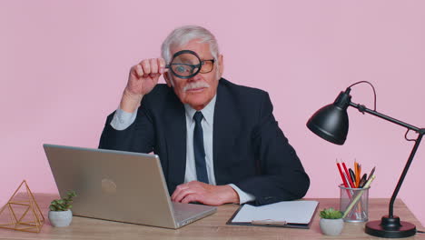 Investigator-senior-businessman-holding-magnifying-glass-near-face-looking-with-big-zoomed-funny-eye