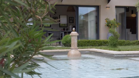 amidst the lush green shrubbery, there stands a house with a pool, where a small waterfall cascades gently