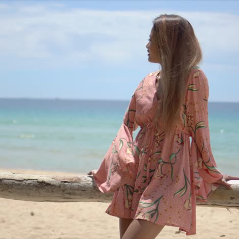 Stylish-woman-leaning-on-fence-on-beach