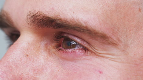 extreme close up of eye as man smiles in studio shot from side