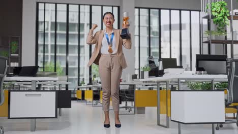 cuerpo lleno de mujer de negocios asiática en un traje con una medalla de oro y trofeo gritando gol celebrando la victoria como el primer ganador en la oficina