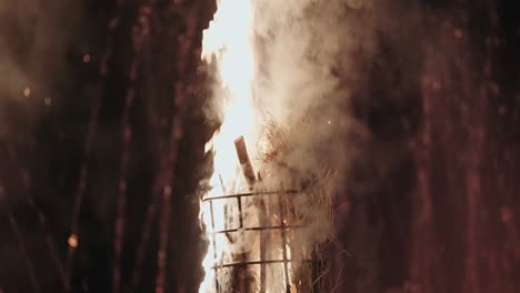 tall wood and straw torch burns intensely with smoke and flames at night
