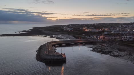 Aerial-time-lapse-of-sunset-over-Barna-Pier-as-lights-turn-on-and-reflect-in-ocean-water