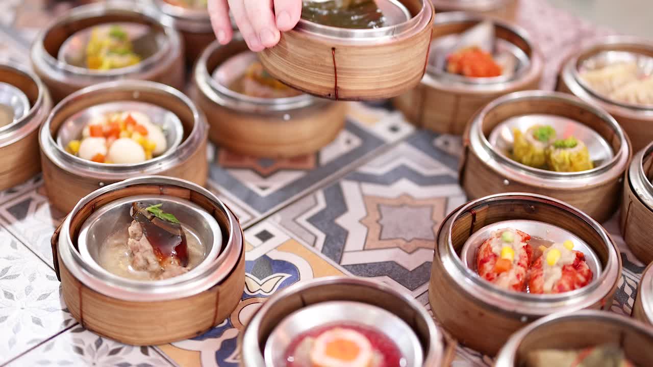 manos seleccionando dim sum de los vaporizadores de bambú