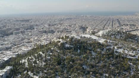 aerial drone view over the filopappou hill, overlooking the snow covered athens city